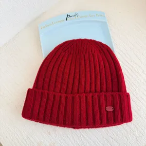 Détail bonnet en laine rouge, bonnet d'hiver chaud avec petite étiquette métal, accessoire douillet.