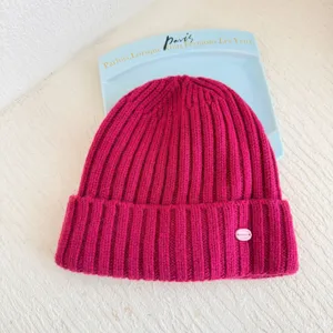 Vue rapprochée détaillée d'un bonnet en tricot côtelé fuchsia vif avec une étiquette rose.