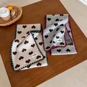 Close up view of cozy knit winter scarf with cute heart pattern and soft texture.