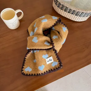 Detail view of the cozy knitted scarf featuring cute blue hearts and brown trim on table.