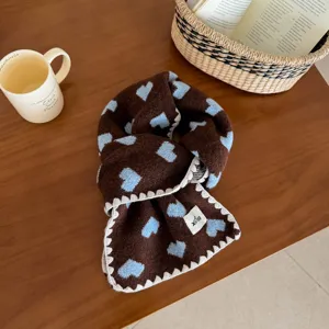 Brown knit scarf featuring blue heart patterns and white scalloped edge details closeup.