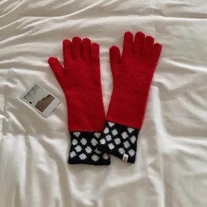 Gros plan détaillé de gants longs en tricot rouge rétro avec des pois bleu marine pour l'hiver.