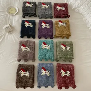 Detailed view of cozy knitted winter scarves featuring cute horse embroidery and sweet pom-poms.
