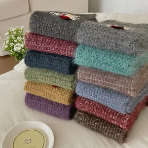 Detailed shot of cozy colorful knitted scarves neatly stacked with cute horse embroidery.