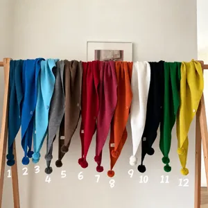 Vue détaillée du foulard triangulaire en tricot doux avec de charmants petits pompons.