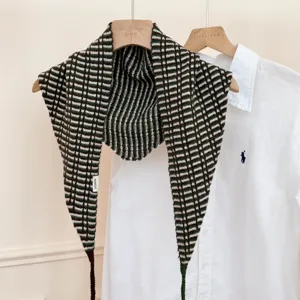 Gros plan détaillé du foulard châle triangulaire en tricot à carreaux vert et marron.
