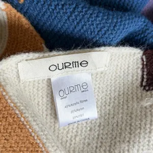 Gros plan détaillé de l'étiquette de marque et de composition du foulard en tricot coloré.