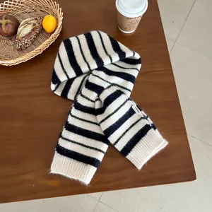 Detail view of a cozy black and white striped wool knit scarf on a wooden table, winter fashion.