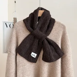 Brown knitted wool scarf detail showcasing soft cable texture and cozy winter neckwear design.