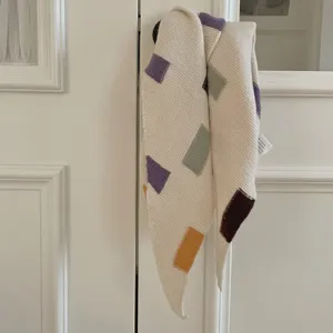 Gros plan détaillé d'une écharpe triangulaire tricotée à blocs de couleurs colorés.