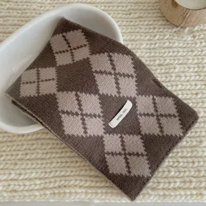 Gros plan détaillé d'une écharpe en tricot argyle marron et beige, texture d'hiver confortable.