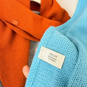 Gros plan détail écharpe en tricot texture douce étiquette marque bouton mélange laine.