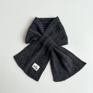 Detailed view of the dark grey knit scarf texture and cute brand label close-up.