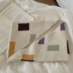 Détail d'écharpe en tricot à blocs de couleur avec motifs géométriques et texture douce.