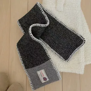 Detail view of wool blend colorblock knit scarf with stylish contrast stitching and woven label.