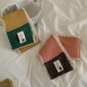 Detailed shot of color-blocked knit winter scarf showing soft wool blend and brand label.