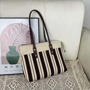 Vue détaillée du sac cabas en tricot rayé avec poignées en cuir et fermeture éclair.