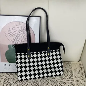 Detail de sac cabas en tricot losange noir et blanc avec poignees solides et fermeture zippee.