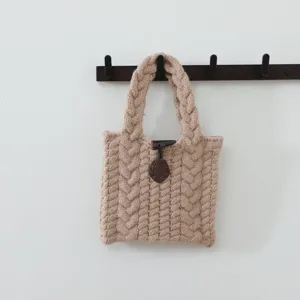Vue détaillée d'un sac à main en tricot torsadé beige douillet avec fermeture à genouillère.