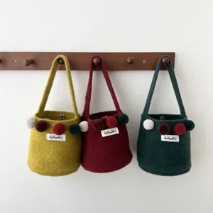 Vue détaillée de sac seau en feutre coloré avec pompons mignons et design élégant.