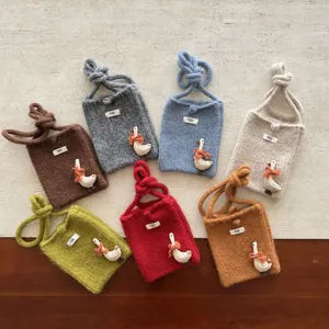 Détail de mini sac de téléphone en tricot avec déco d'oie et divers coloris sympas.