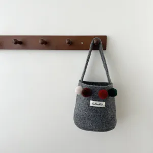 Gros-plan sac seau en feutre gris avec pompons colorés suspendu patère en bois, chic.