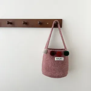 Vue de détail du joli sac seau en feutre de laine coréen avec de charmants pompons colorés.