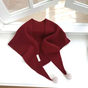 Gros plan détaillé du foulard en laine bordeaux montrant une douce texture tricotée et des pompons.