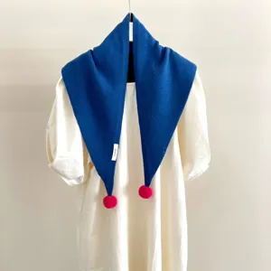 Vue détaillée d'une écharpe triangulaire en tricot 100% laine avec de beaux pompons roses.