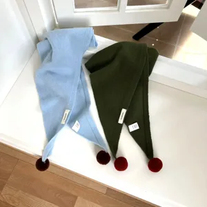 Gros plan d'écharpe en tricot 100% laine avec pompon en bleu clair et vert foncé.