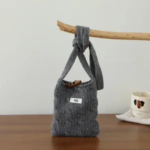 Sac bandoulière gris en tricot torsadé avec bouton en bois et mini pochette en laine.