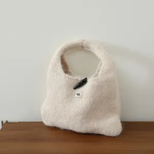 Détail de sac à main en mohair tricoté, sac cabas automne hiver douillet avec bouton corne.