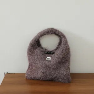 Gros plan détail du sac à main tricoté en mohair pelucheux avec bouton et étiquette.