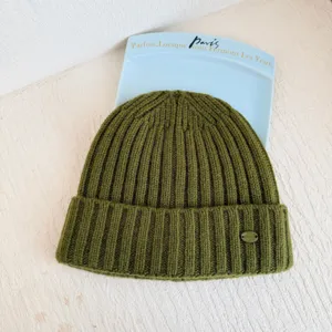 Bonnet en tricot de laine vert olive avec motif côtelé et logo métallique pour l'hiver froid.