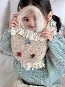 Detailaufnahme der süßen Stricktasche aus weicher Wolle mit filigraner Spitze und Pilzen.