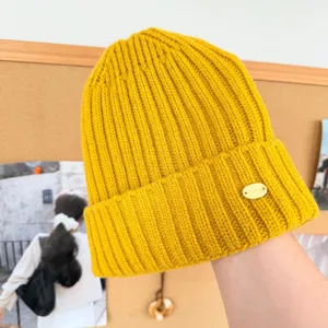 Détail de bonnet tricoté jaune, bonnet d'hiver chaud en laine avec logo métallique.