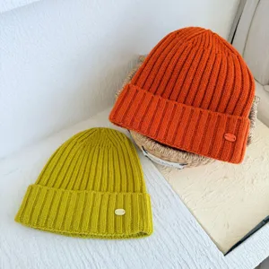 Vue détaillée de bonnet en tricot de laine douillet orange et jaune, chapeau chaud.