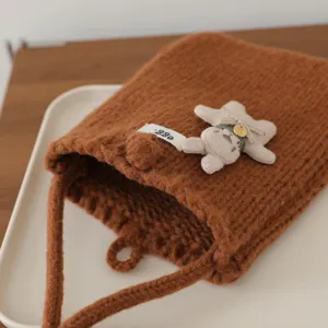 Gros plan du petit sac en tricot marron douillet avec joli lapin en peluche et étiquette.