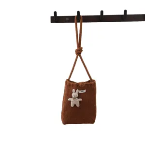 Petit sac bandoulière tricoté marron avec pendentif peluche lapin mignon suspendu au crochet.