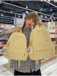 Joli sac à dos jaune brodé d'étoiles avec un pendentif poupée en peluche mignon pour les étudiants.
