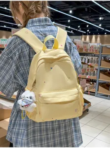 Vue détaillée du sac à dos jaune avec des étoiles colorées et un joli pendentif en peluche.