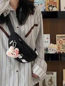 Black canvas chest bag detail, cute plush rabbit pendant, casual crossbody lifestyle shot.