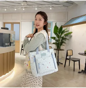 Detailed view of the light blue patterned tote bag with front zipper pockets and straps.