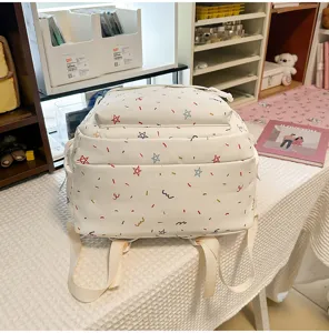 Detailed view of white student backpack with colorful star and doodle pattern on desk.