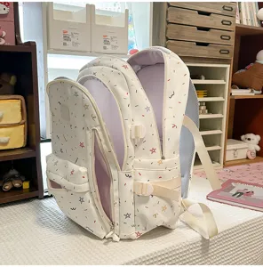 Detailed view of white multi-layer student backpack with colorful star doodle patterns.