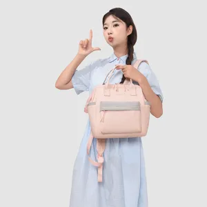 Sac à dos à langer rose léger avec multiples compartiments et poche avant grise élégante.