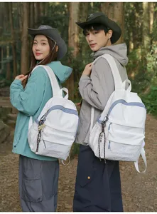 Detail view of stylish white casual backpack with blue trim and pocket design outdoors.