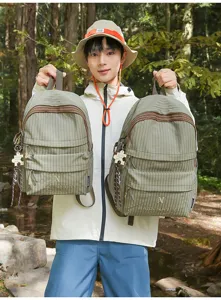 Detailed view of casual green plaid backpack with front pocket and cute puzzle pendant accessory.