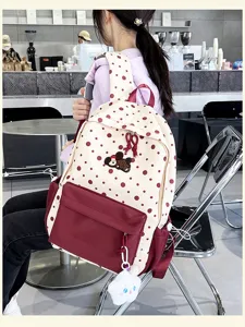 Detailansicht des süßen beige-roten Polka-Dot-Rucksacks mit Plüsch-Anhänger im Café-Ambiente.