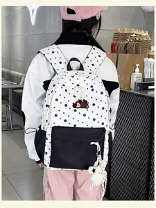 Detaillierte Ansicht des stilvollen gepunkteten Rucksacks mit niedlichen Anhängern und Taschen.